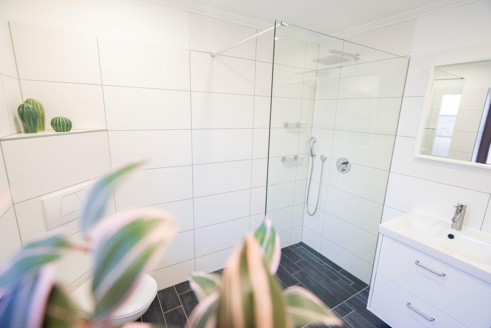 Modernes Badezimmer der Ferienwohnung Bergmoment in Blankenburg Harz mit geräumiger ebenerdiger Dusche.