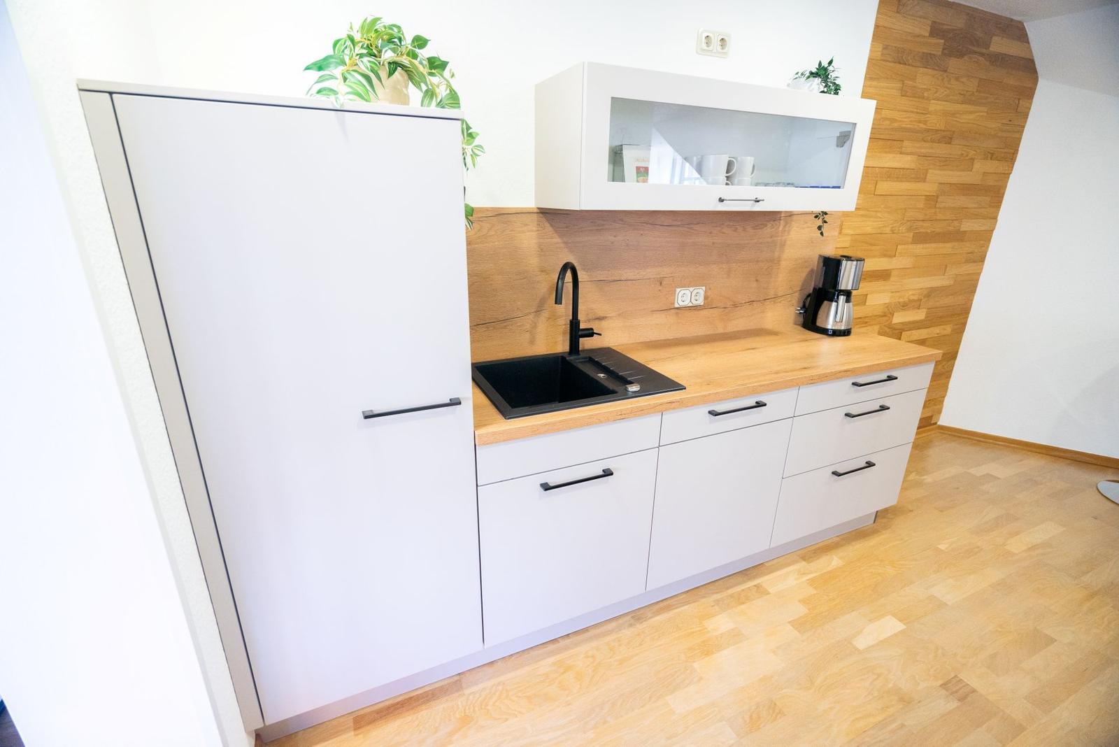 Moderne Kueche der Ferienwohnung Bergmoment in Blankenburg Harz mit Induktionskochfeld, Backofen, Geschirrspueler und Mikrowelle.