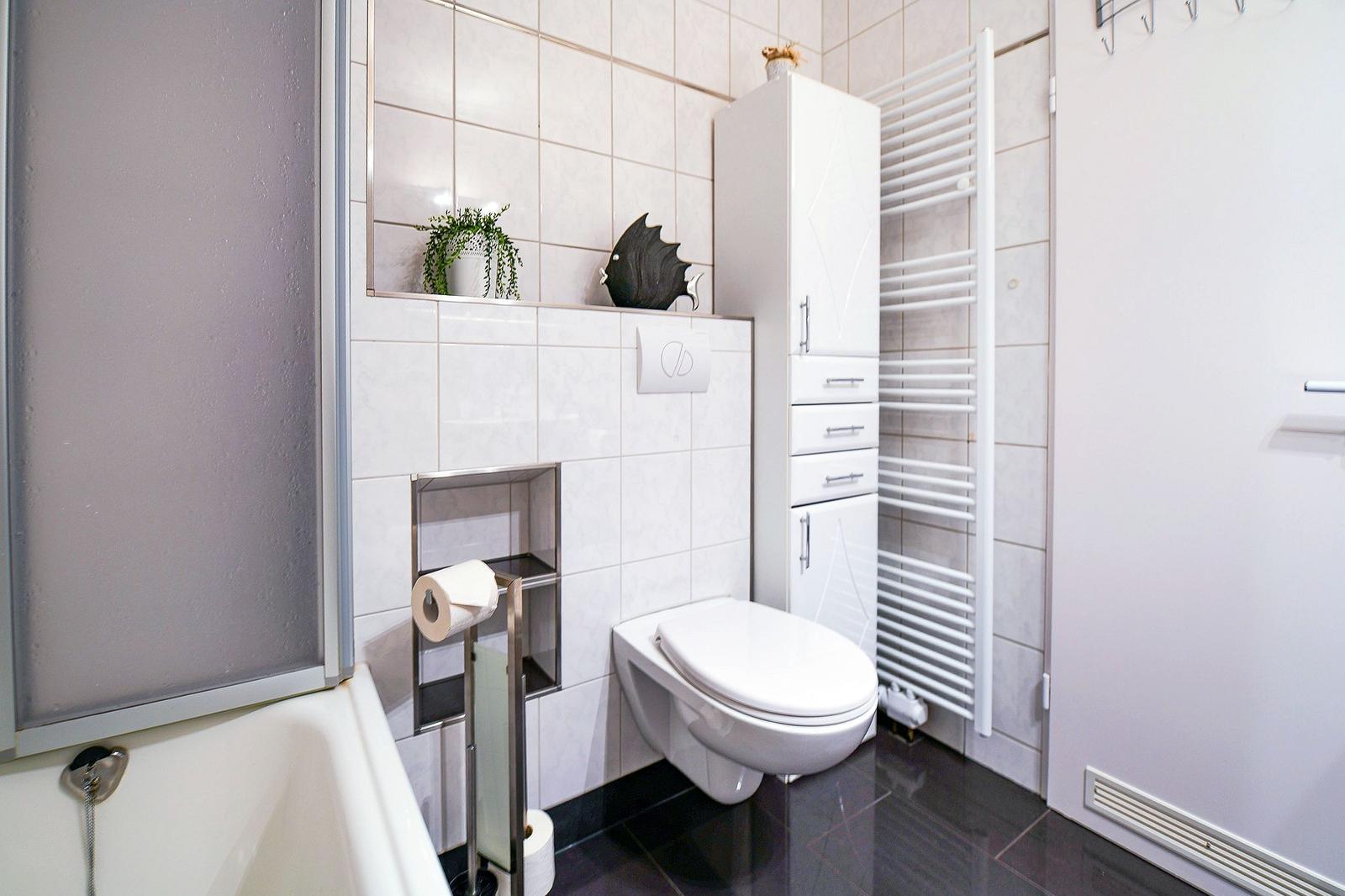 Badezimmer mit Toilette, Duschwanne und Heizkörper
