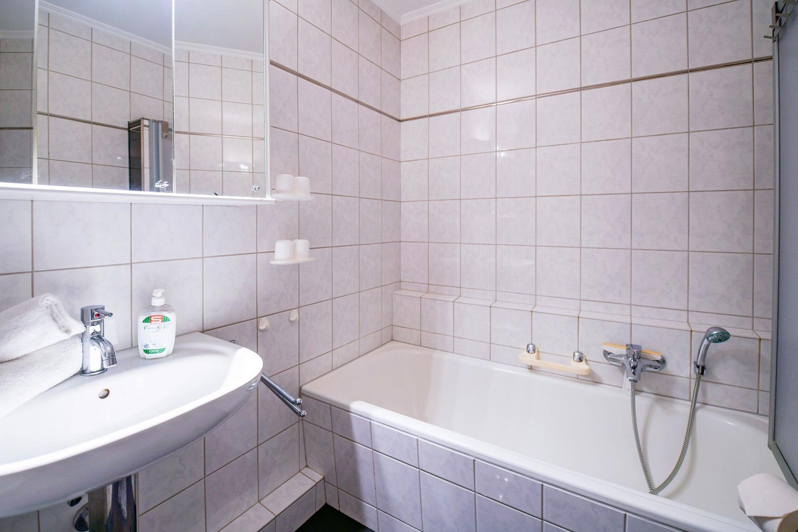 Badezimmer mit Badewanne, Waschbecken und Spiegel.