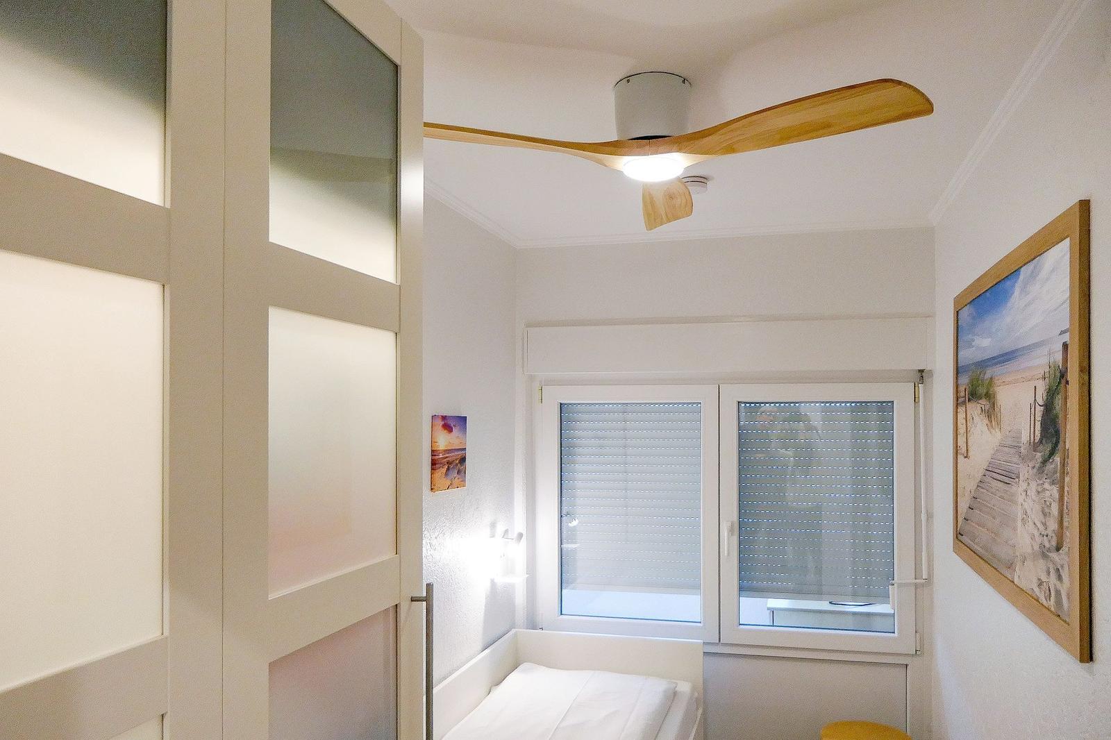 Schlafzimmer mit Bett, Fenster und Deckenventilator.