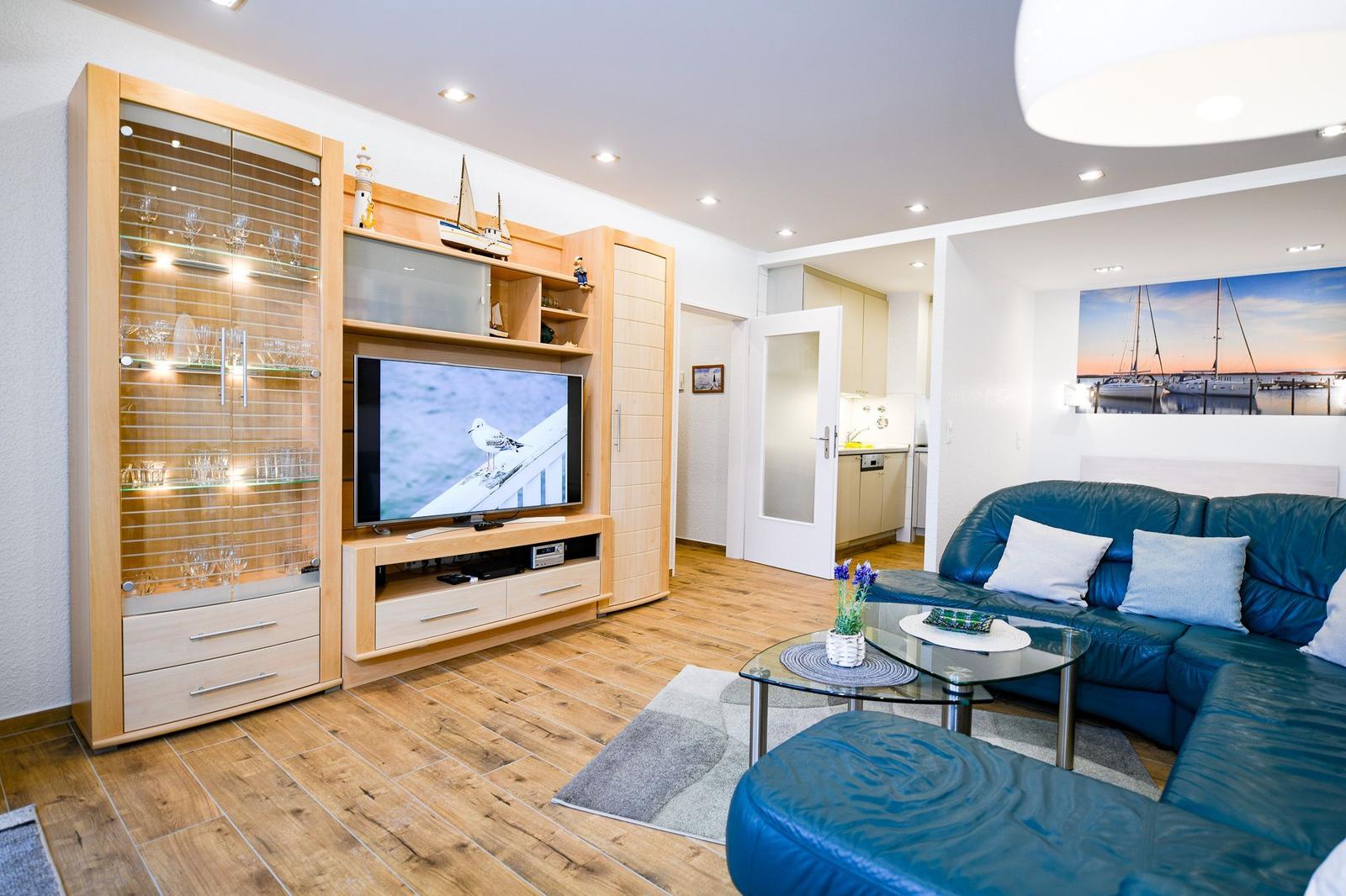 Wohnzimmer mit blauem Sofa, Fernseher und Holzboden.