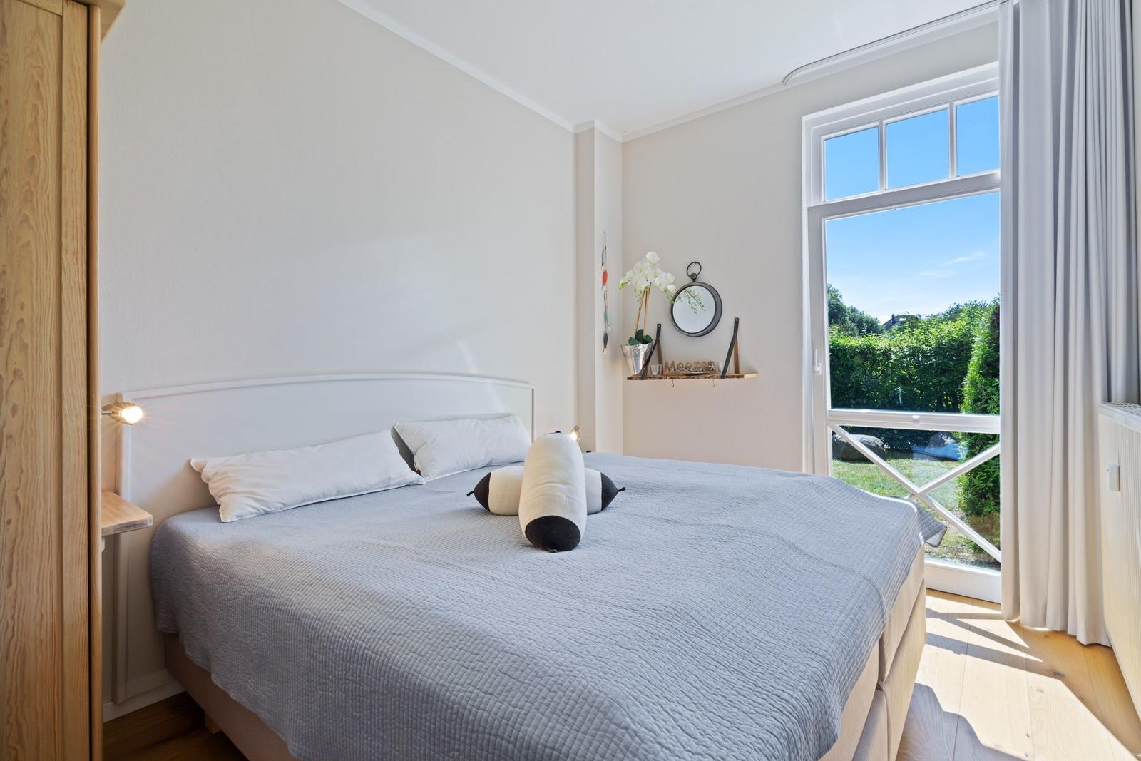 Schlafzimmer mit Bett, Fenster und Holzboden.