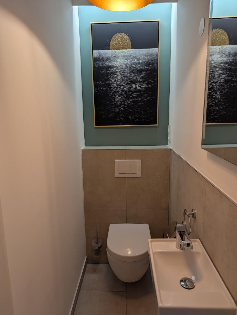 Badezimmer mit Toilette, Waschbecken und Wandbild.