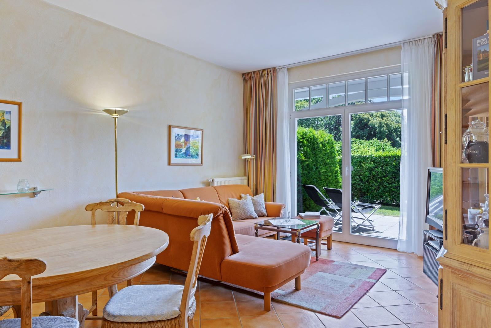 Wohn- und Essbereich mit Sofa, Tisch und Blick auf Garten.