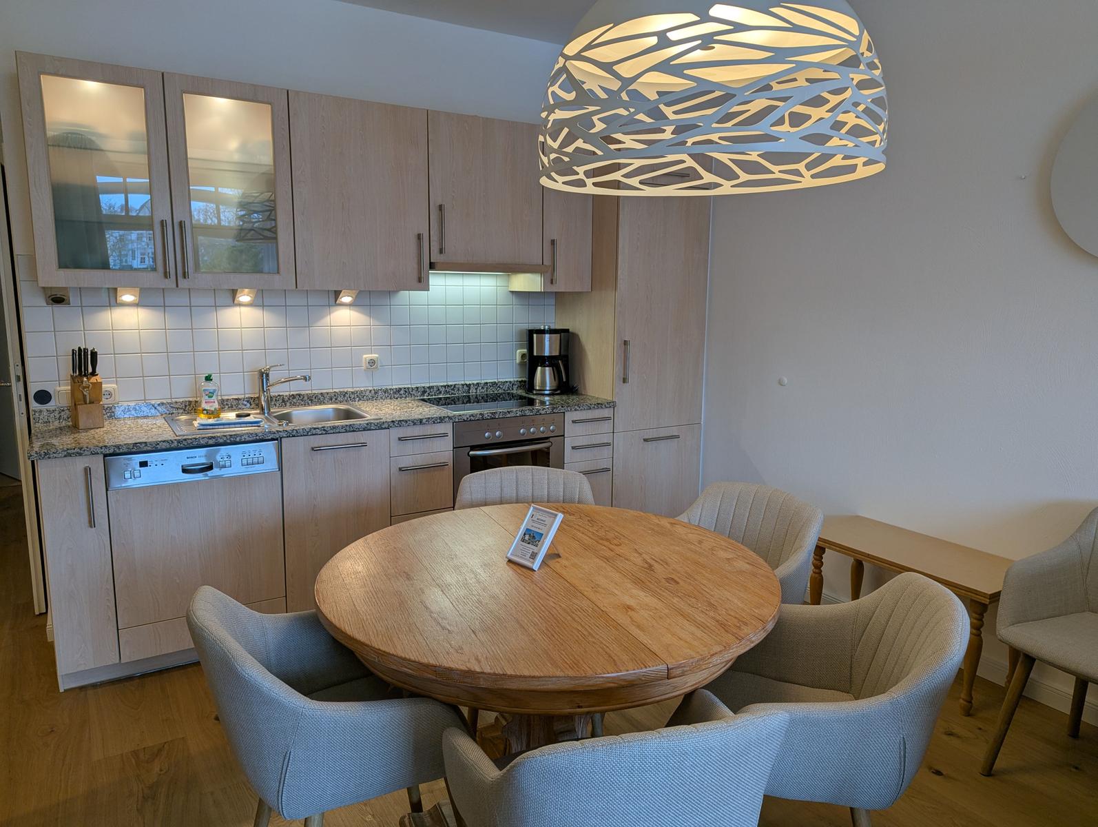 Küche mit Essbereich, Holztisch und moderner Deckenleuchte.