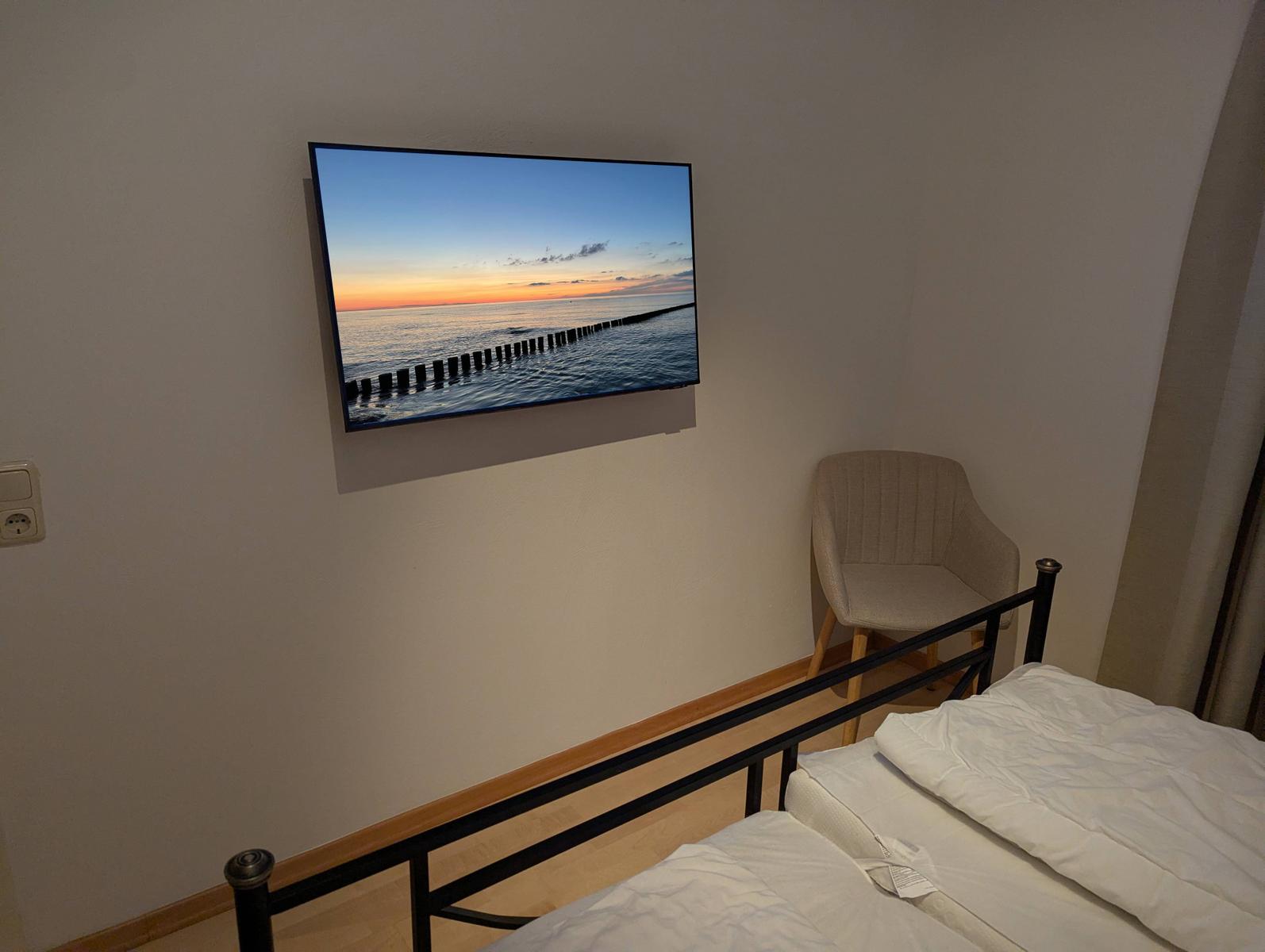 Schlafzimmer mit Bett, Stuhl und Wandbildschirm