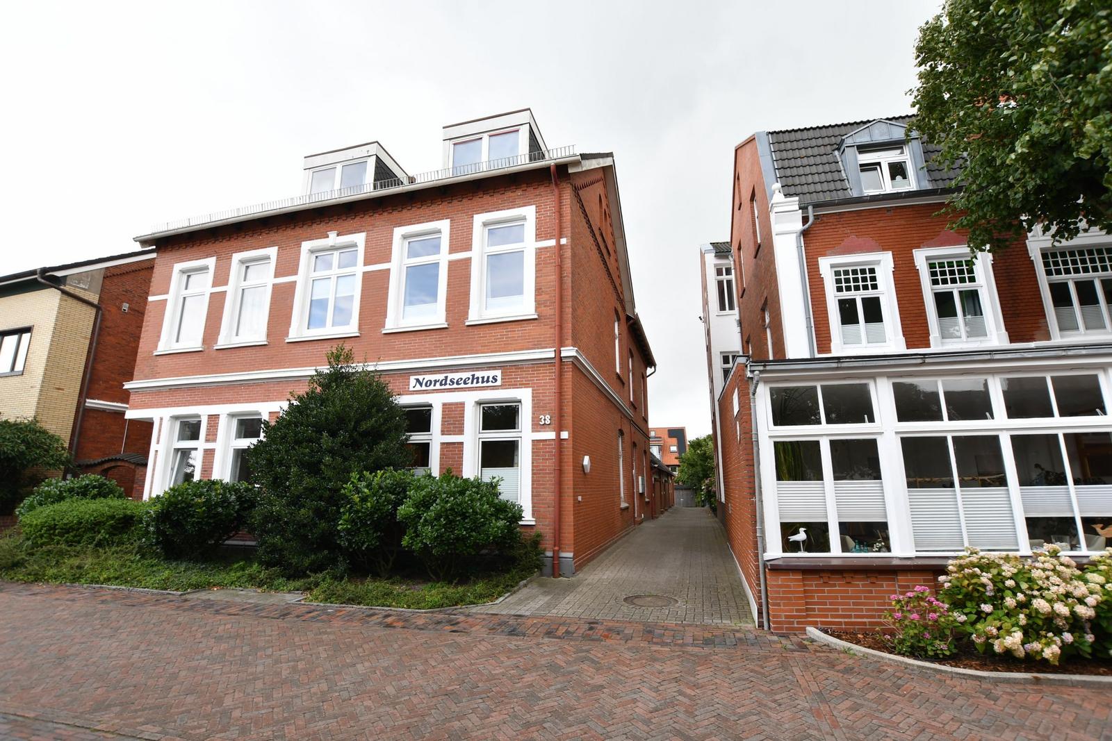 Rotes Backsteinhaus mit weißen Fensterrahmen und Schild Nordseehaus