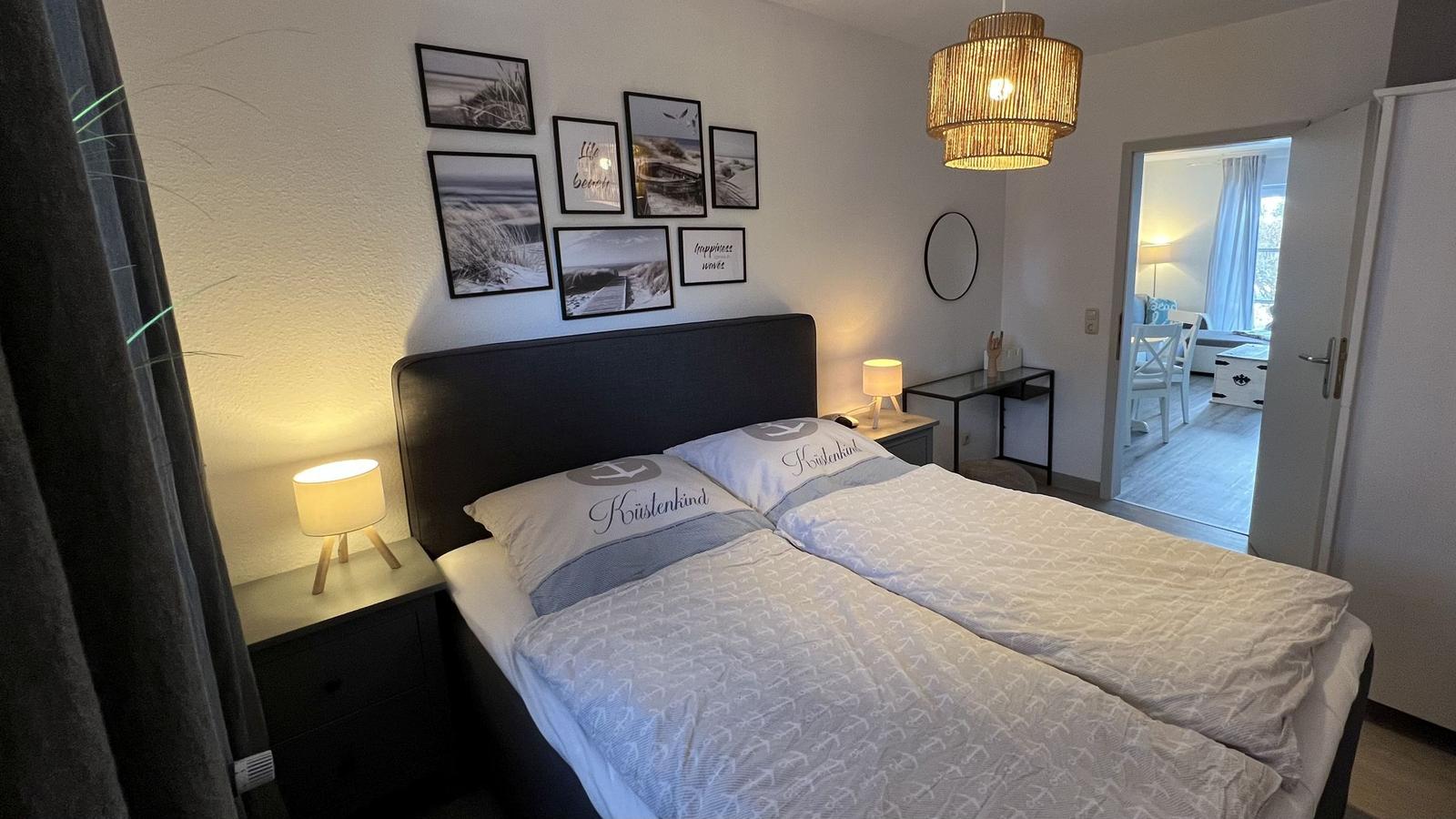 Schlafzimmer mit Doppelbett, Wandbildern und Nachttischen.