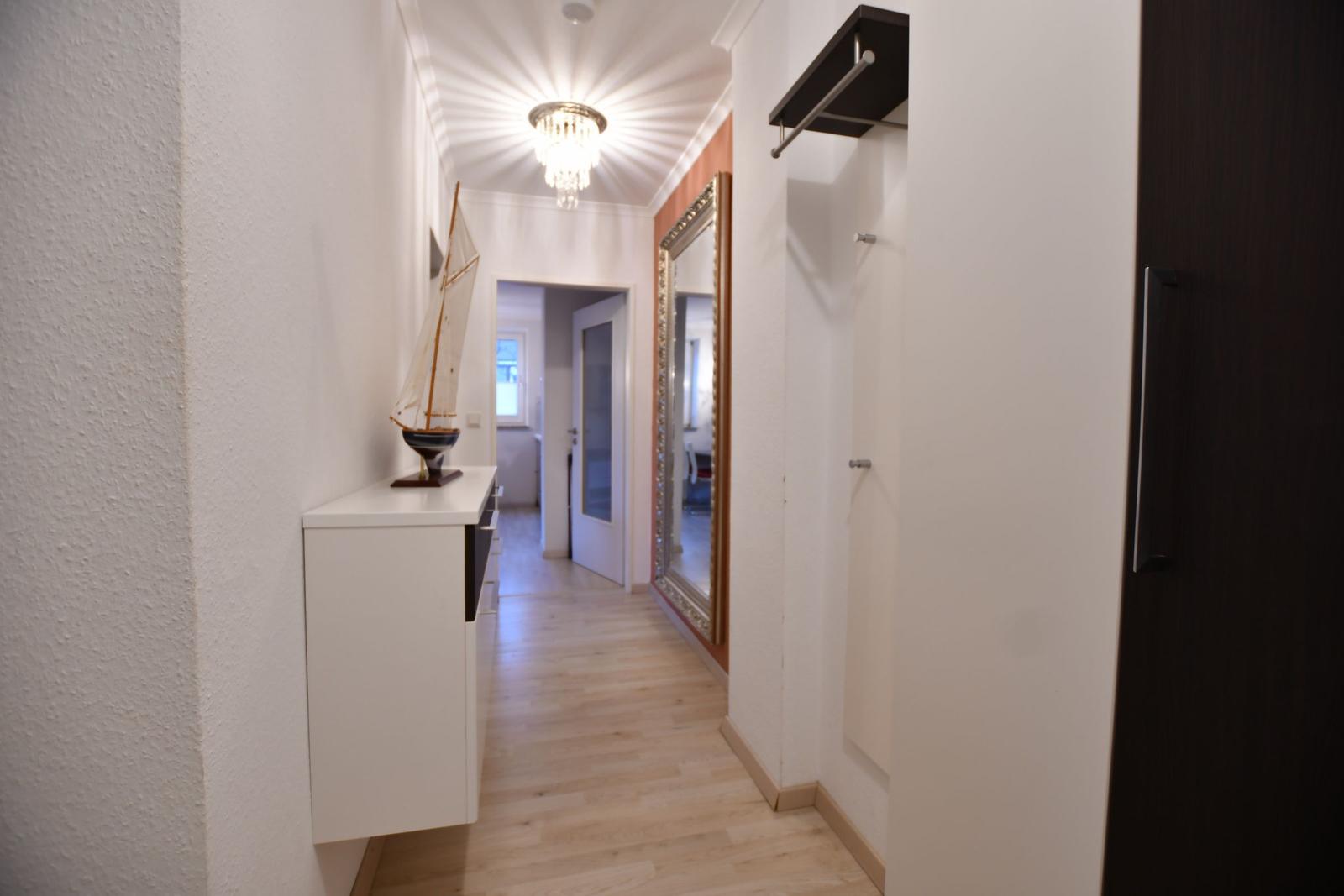 Flur mit Holzboden, Spiegel und Modellboot auf Schrank.