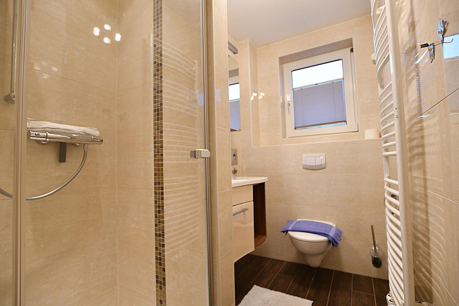 Badezimmer mit Dusche, Toilette und Waschbecken.