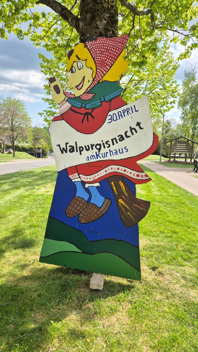 Holzschild mit Walpurgisnacht-Veranstaltungsinformation am Kurhaus.