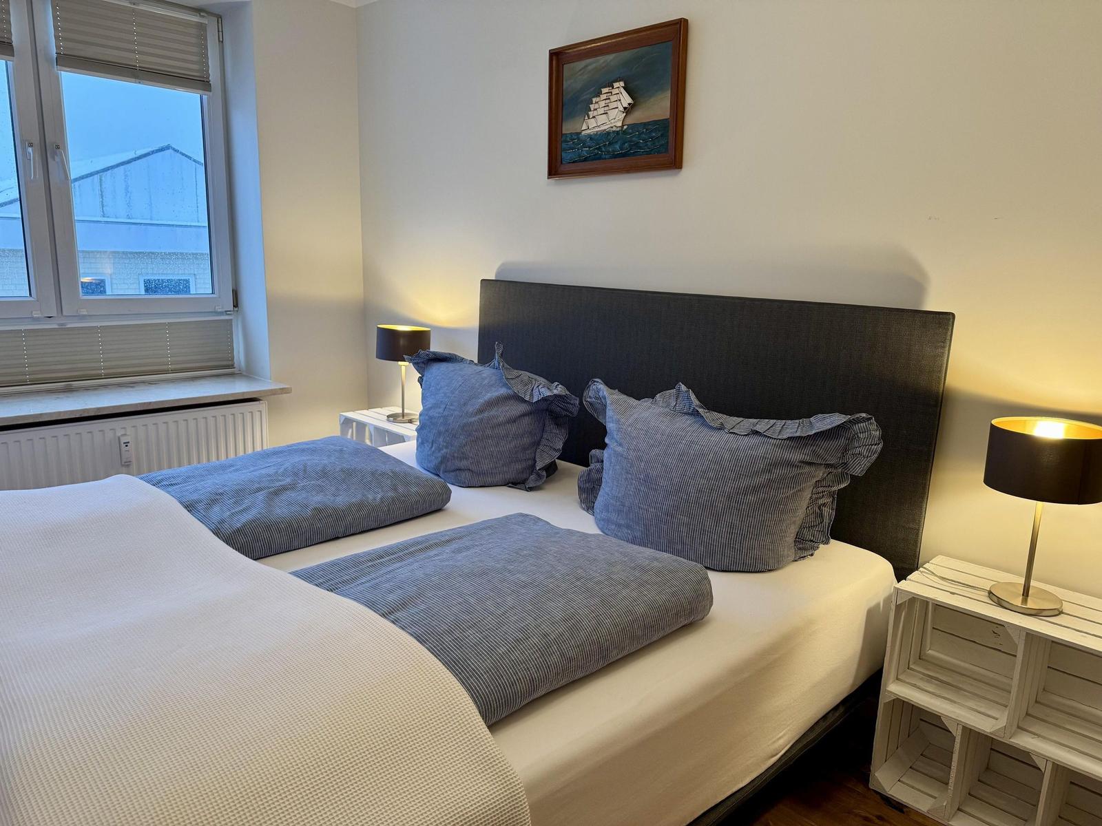 Schlafzimmer mit Bett, zwei Nachttischen und Bild an der Wand.