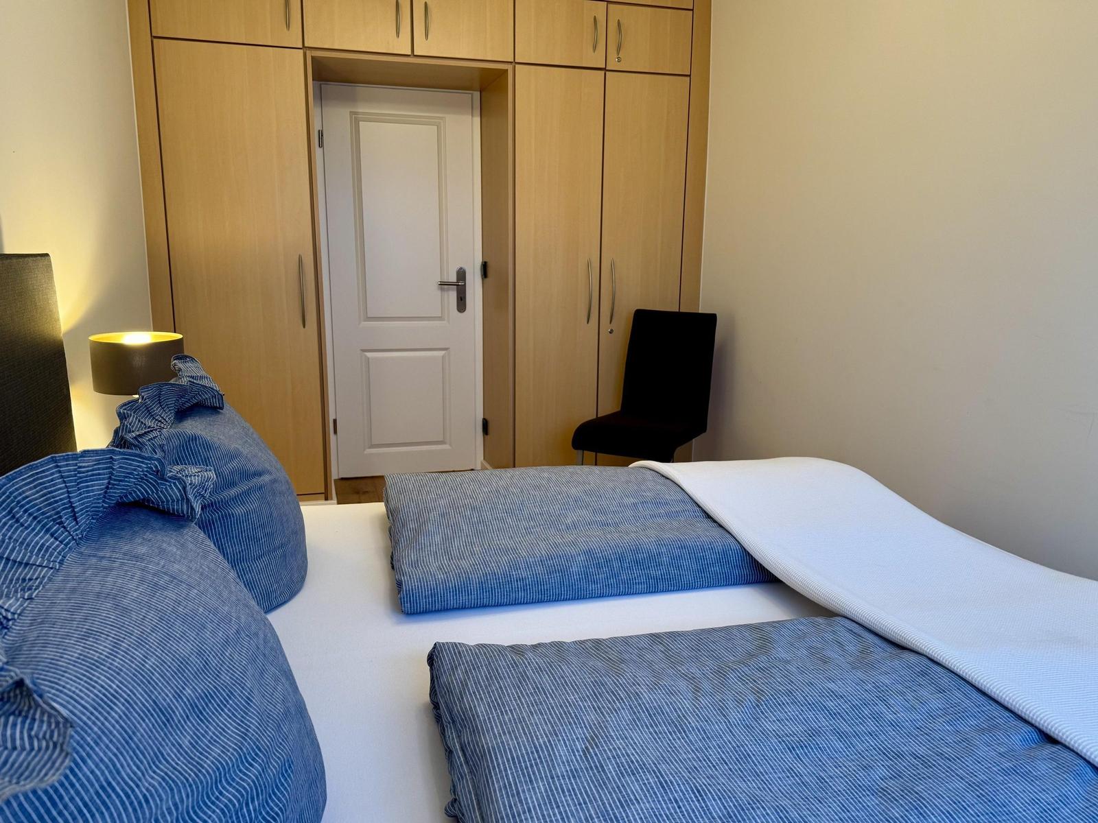 Schlafzimmer mit Doppelbett, Kleiderschrank und Stuhl.