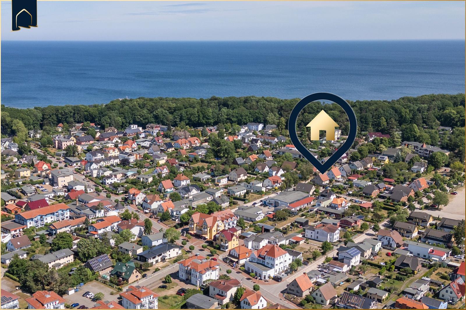 Aerial view of a coastal town with houses and forest near the sea.