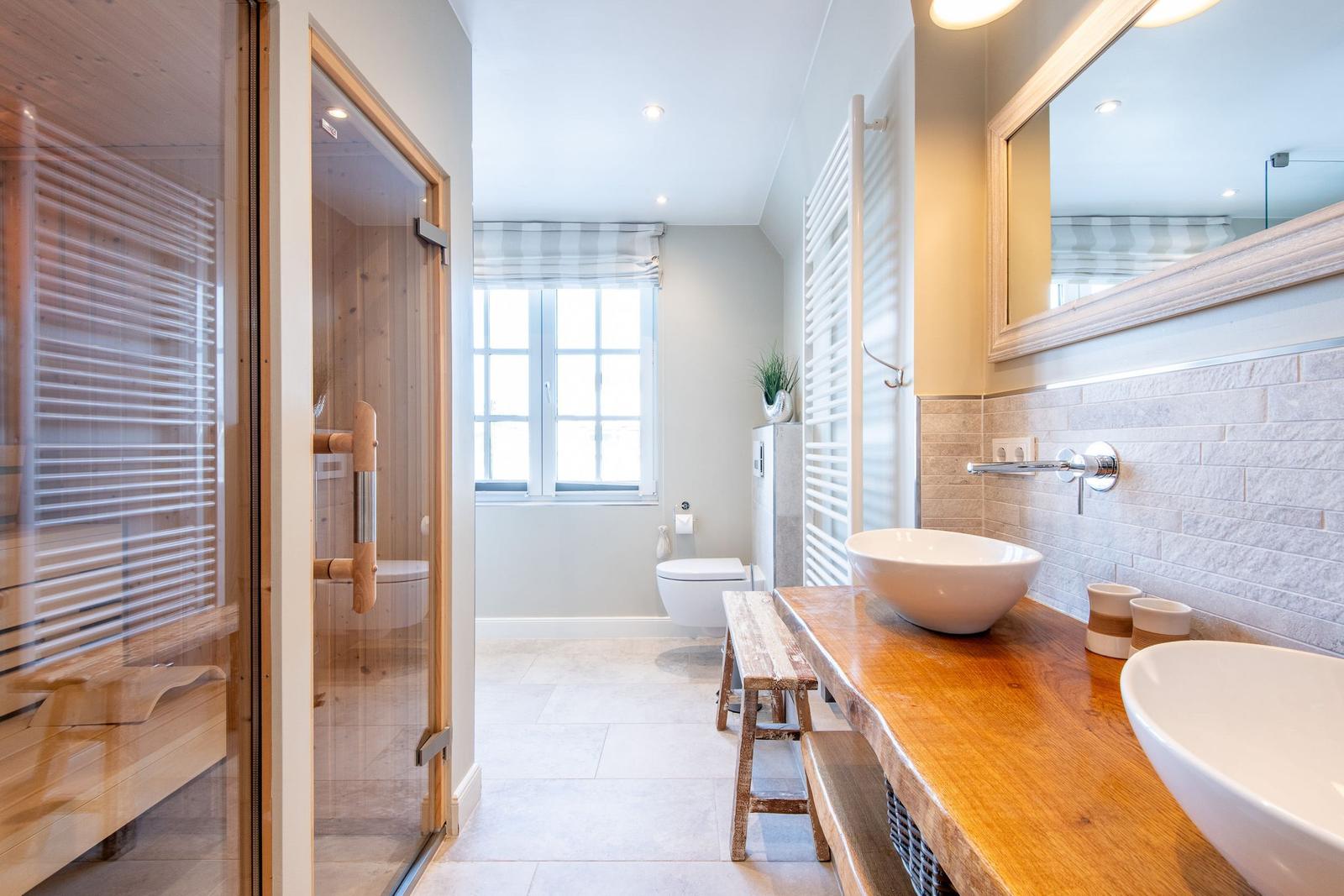 Badezimmer mit Dusche, Toilette und Waschbecken auf Holzkonsole.