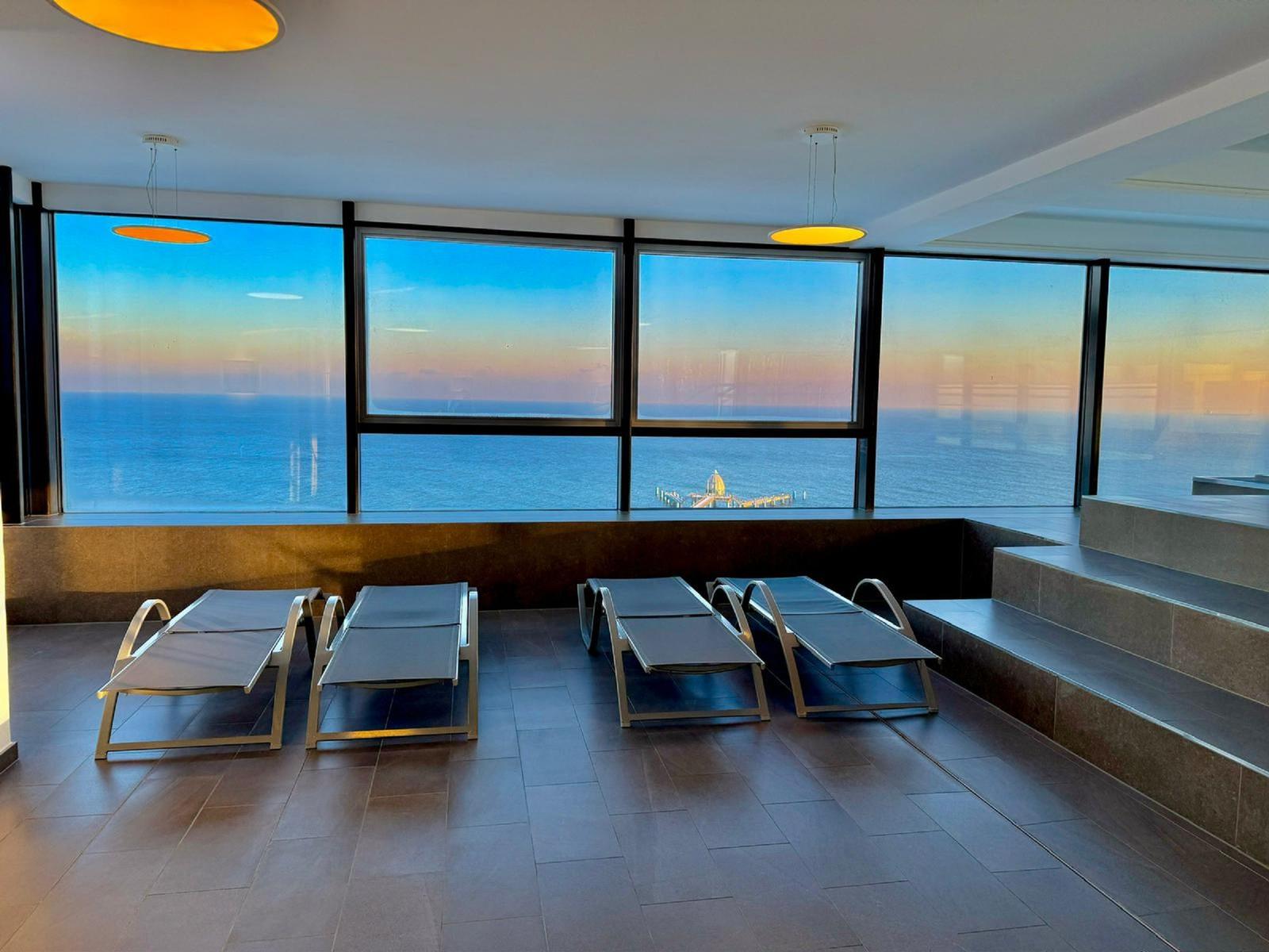 Terrasse mit Liegestühlen und Blick auf das Meer bei Sonnenuntergang.