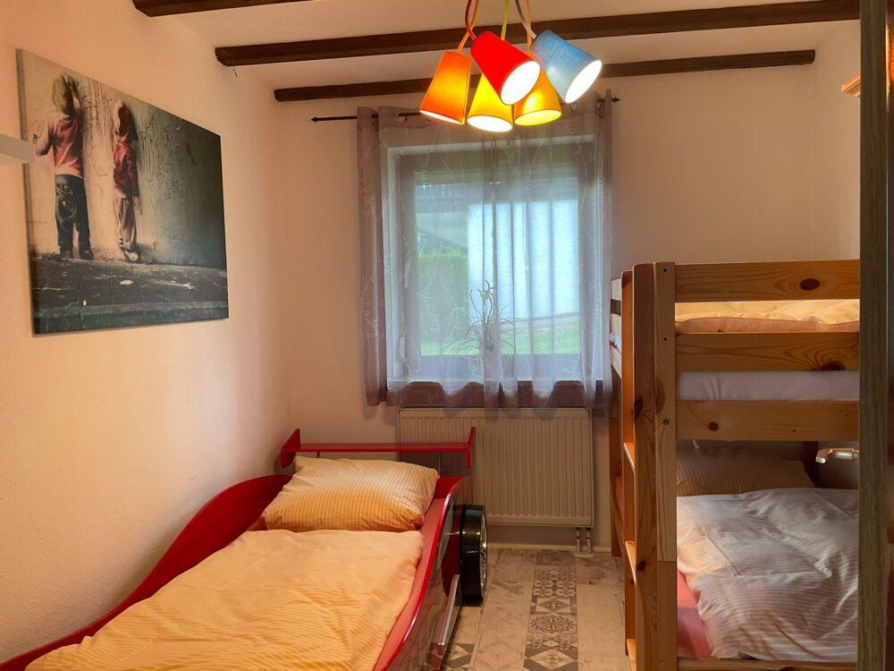 Room with sofa bed, bunk bed, and window with curtains.