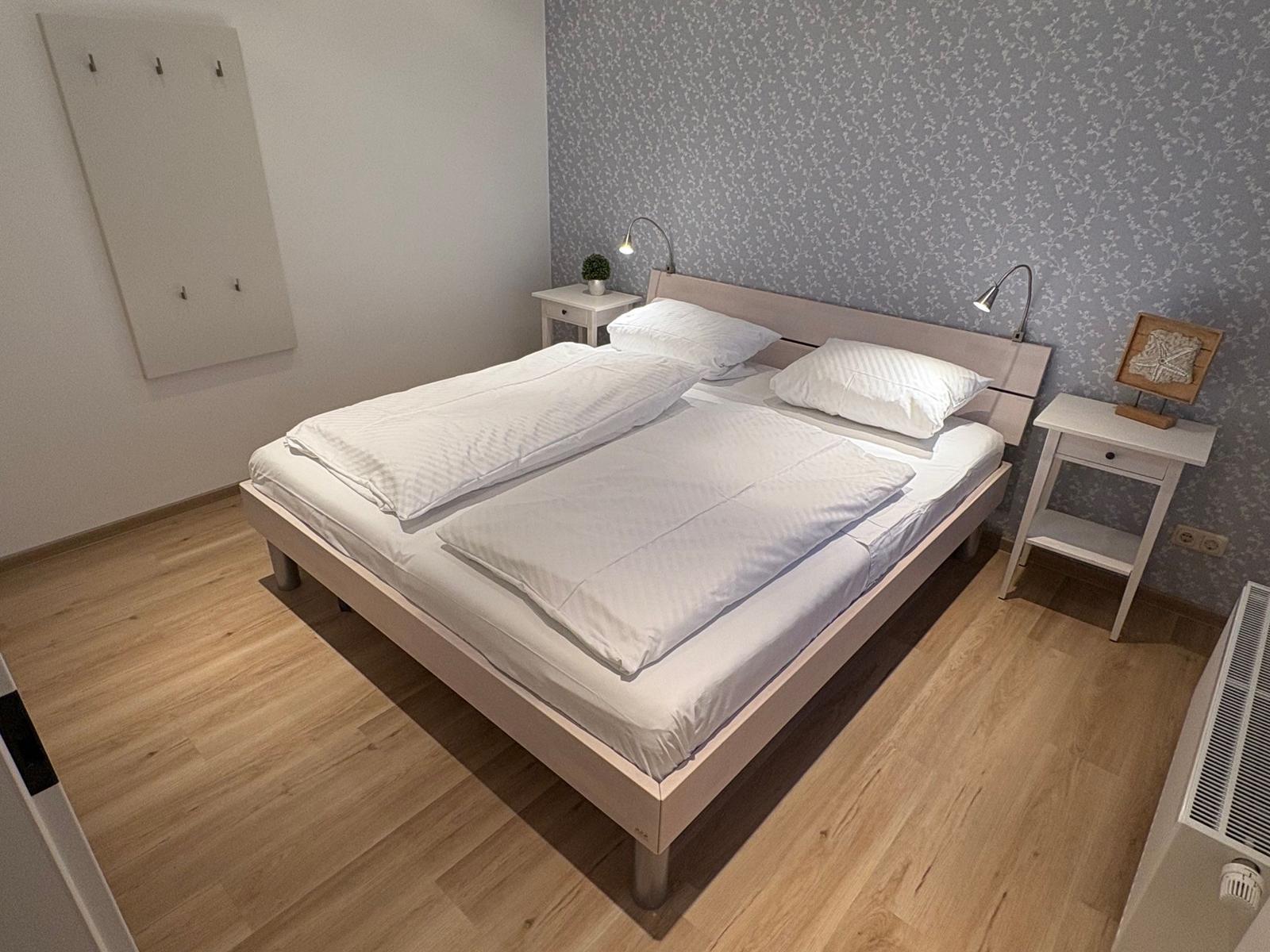 Schlafzimmer mit Doppelbett, zwei Nachttischen und Holzboden.