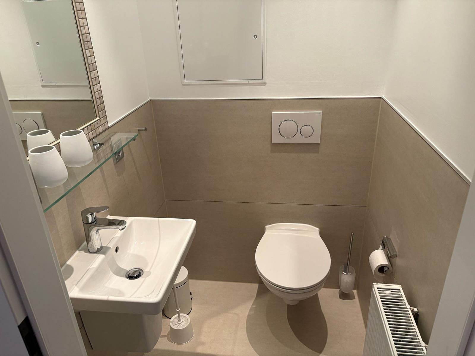 Badezimmer mit Toilette, Waschbecken und Spiegel.