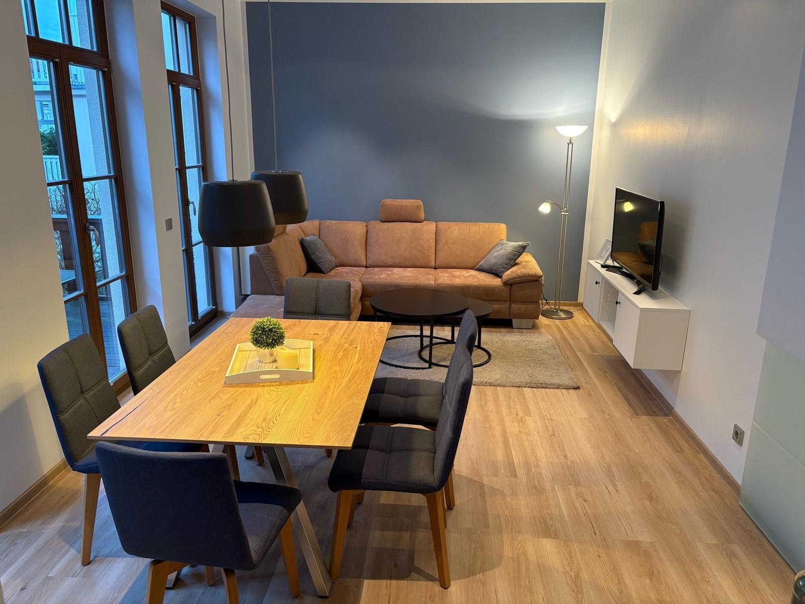 Wohn- und Essbereich mit Sofa, Esstisch und Fernseher.