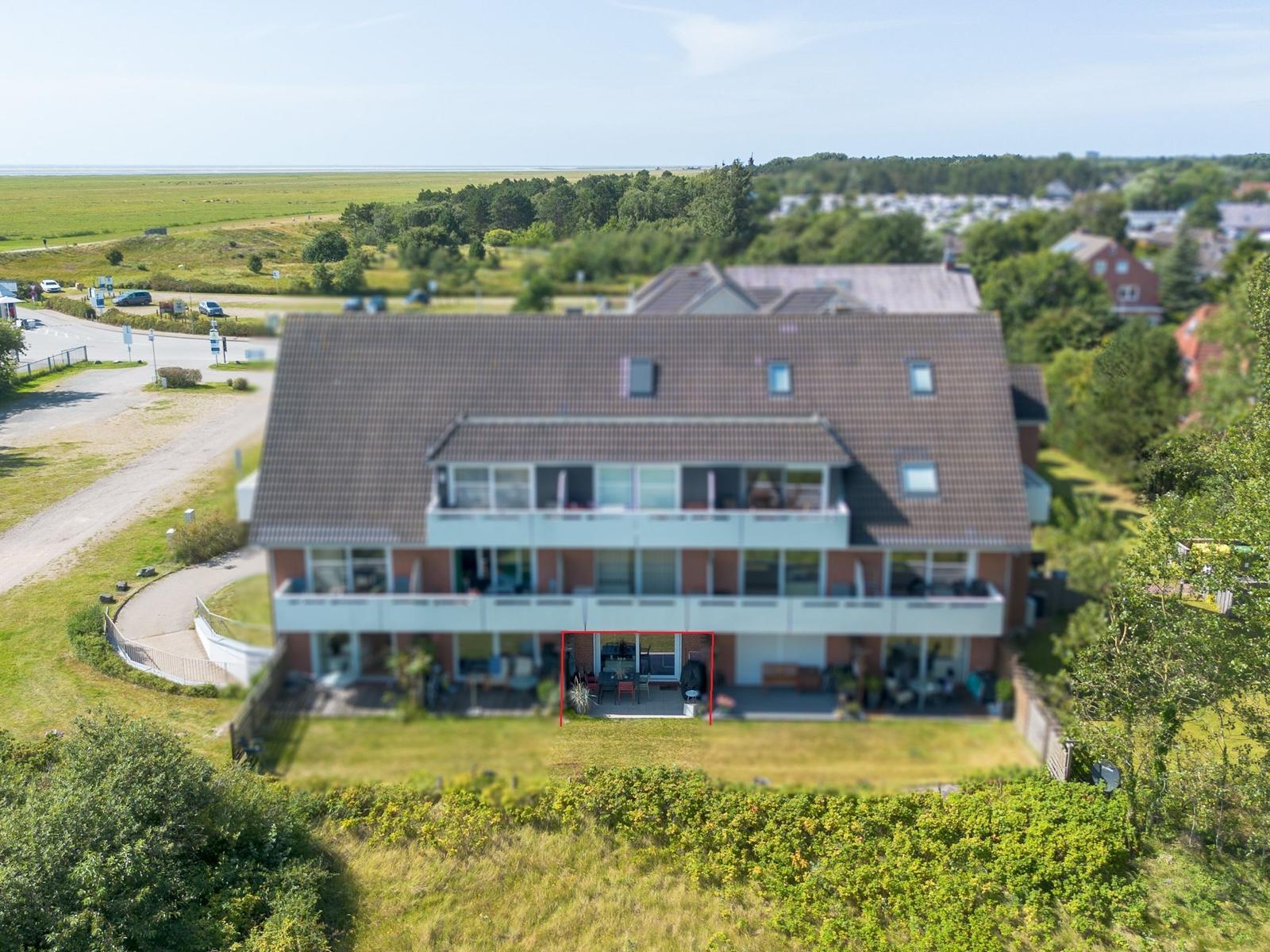 Ein Haus mit Balkon und Terrasse, umgeben von Grünflächen und Wald.