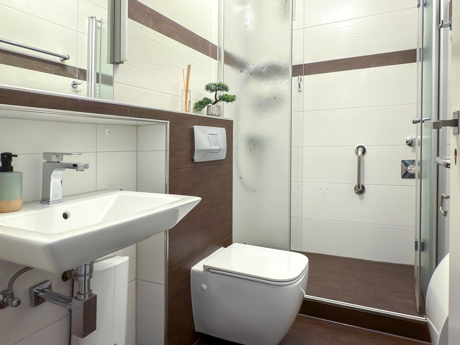 Badezimmer mit Dusche, Toilette und Waschbecken mit Spiegel.