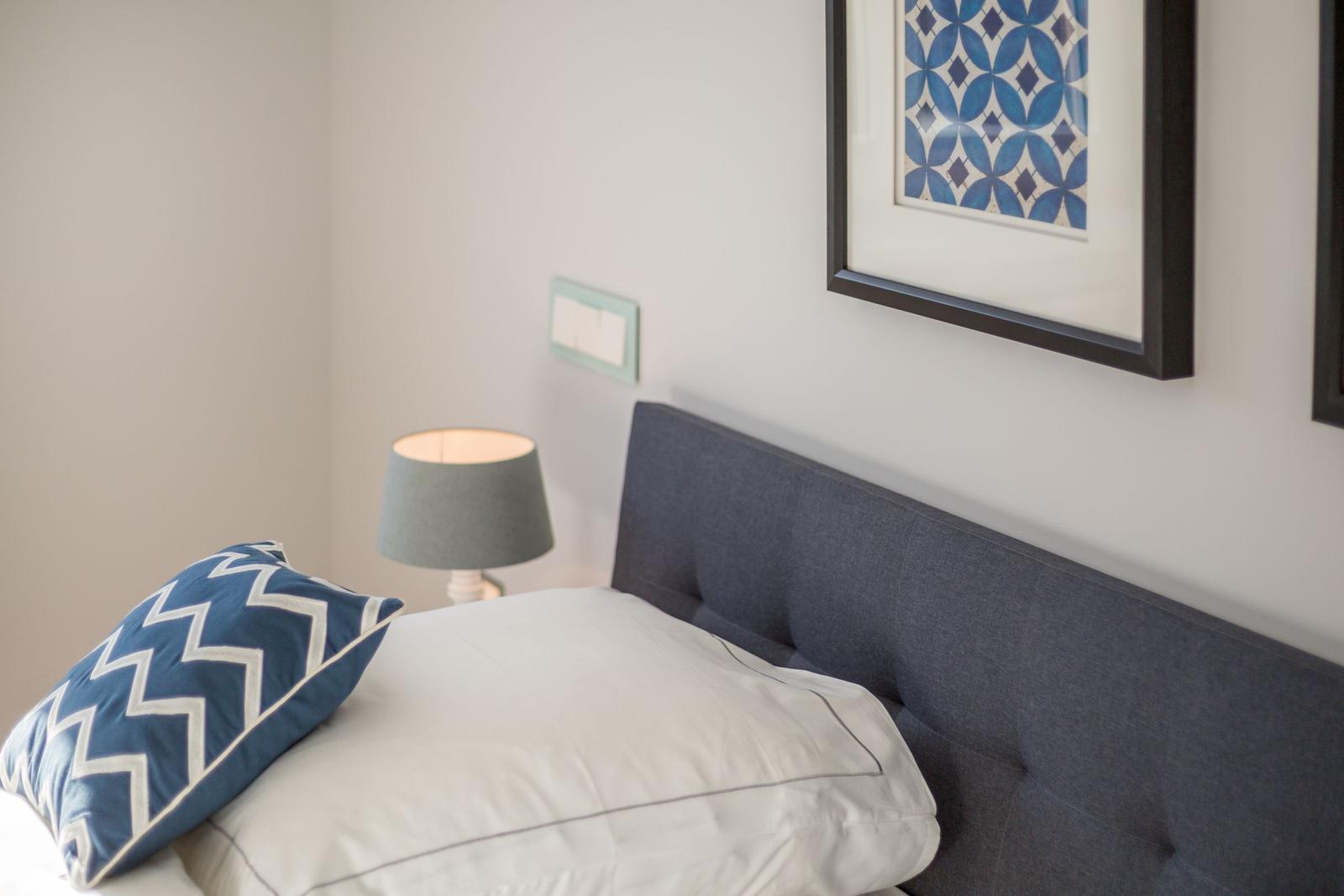 Schlafzimmer mit Bett, Kissen und Wandbild.