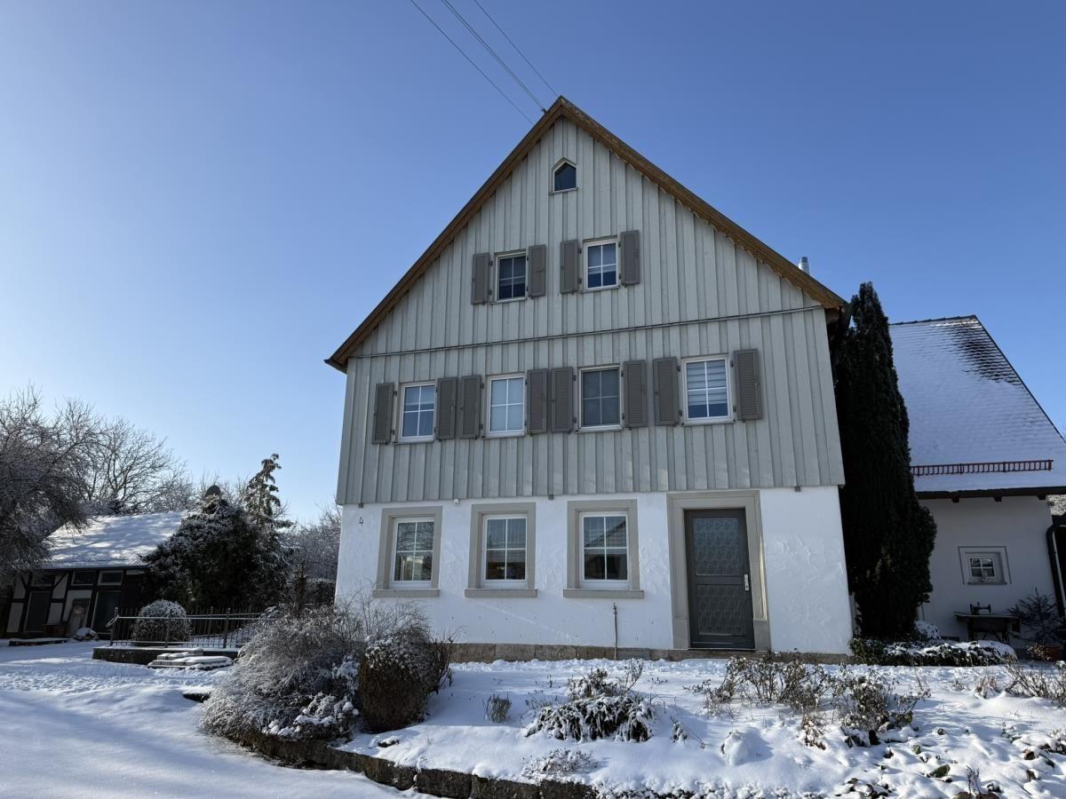 Haus mit Schnee bedecktem Grundstück und Fenstern mit Läden
