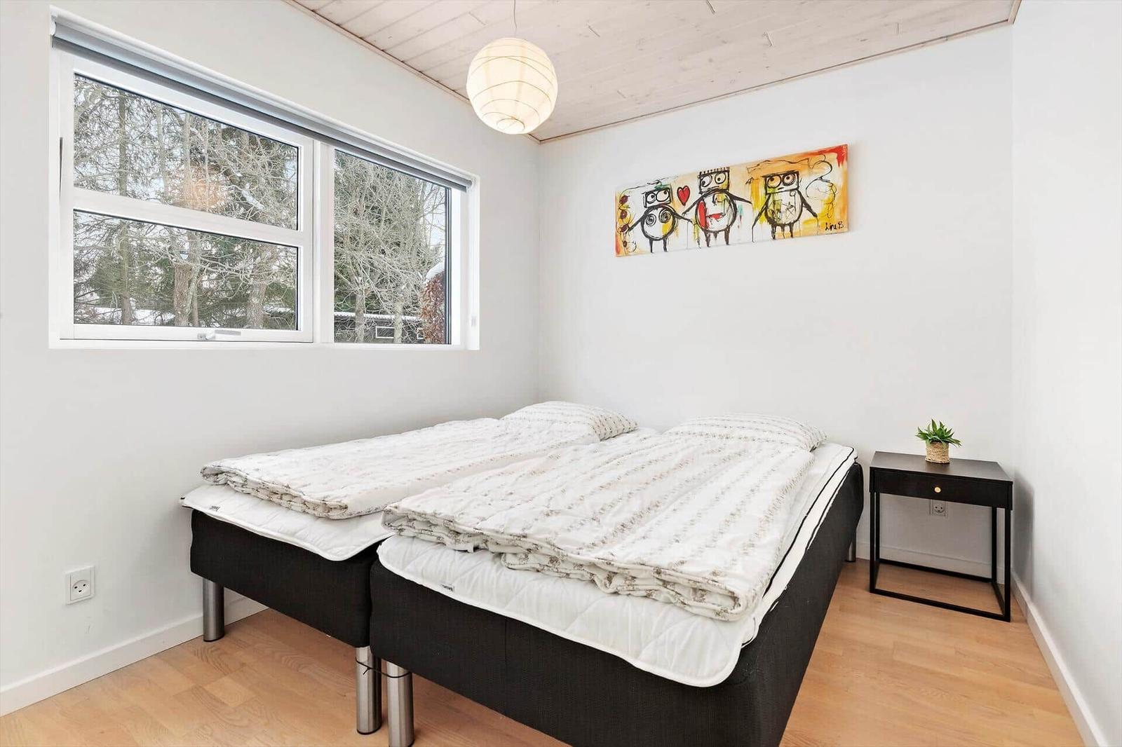 Bedroom with double bed, window, and wall art.