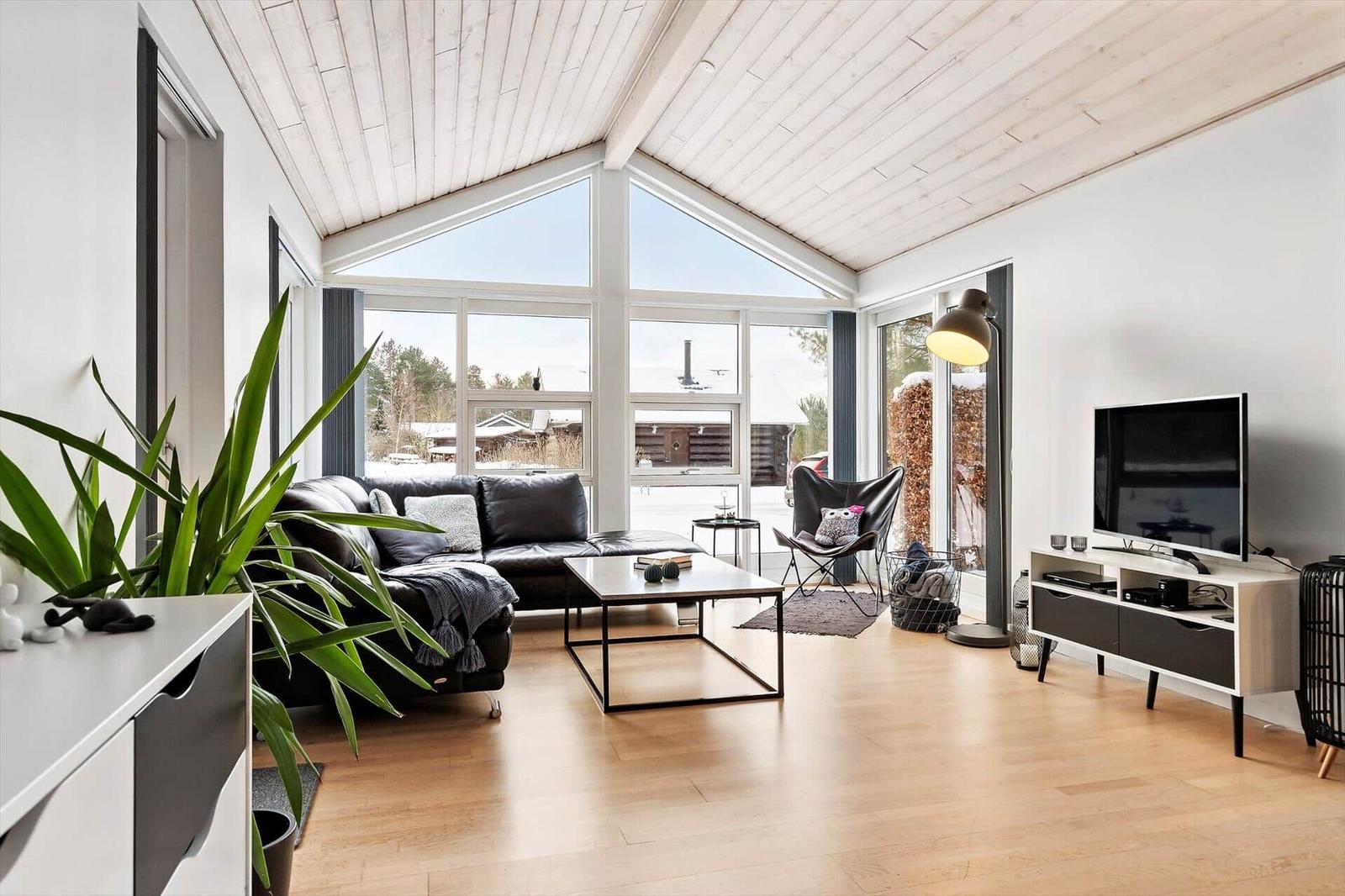 Living room with large windows, sofa, coffee table, and TV.