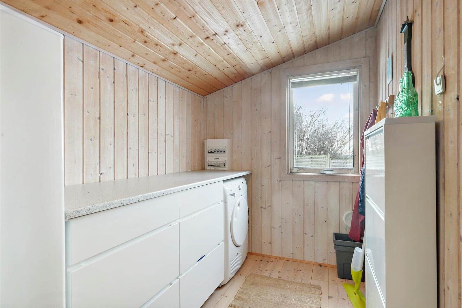 Apartment with wooden walls, washing machine, and window to outdoor area.