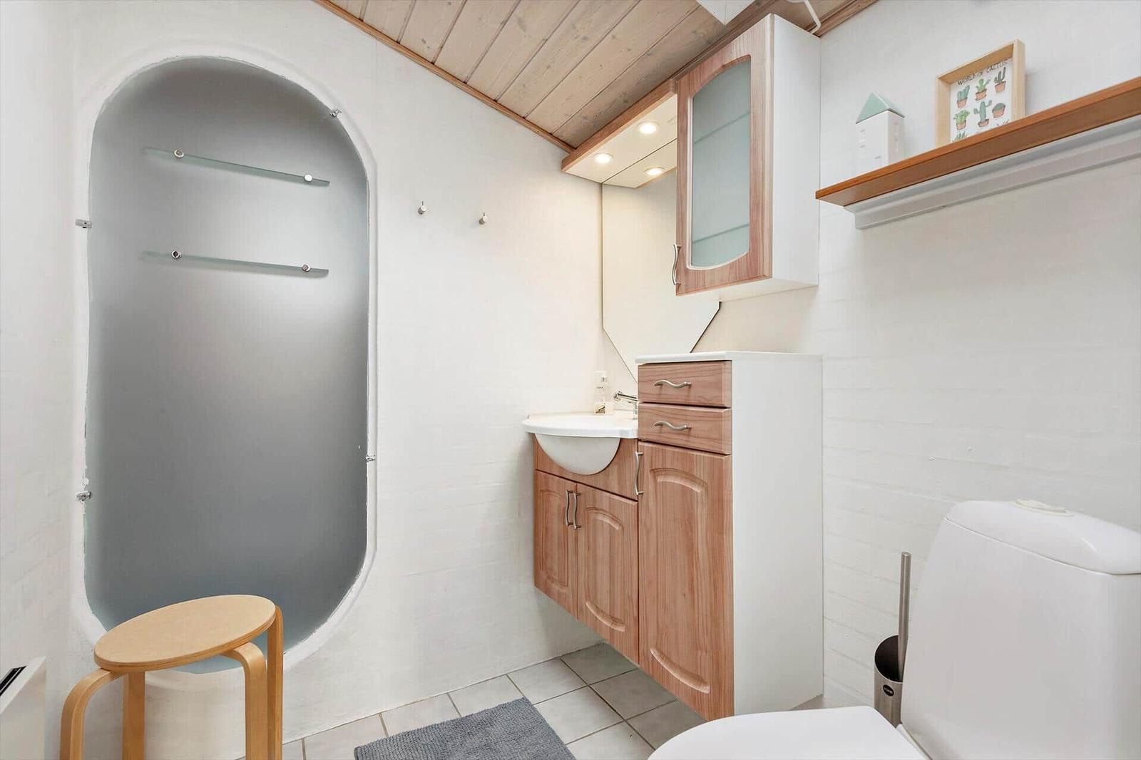Bathroom with shower, sink and toilet. Wooden ceiling and fixtures.