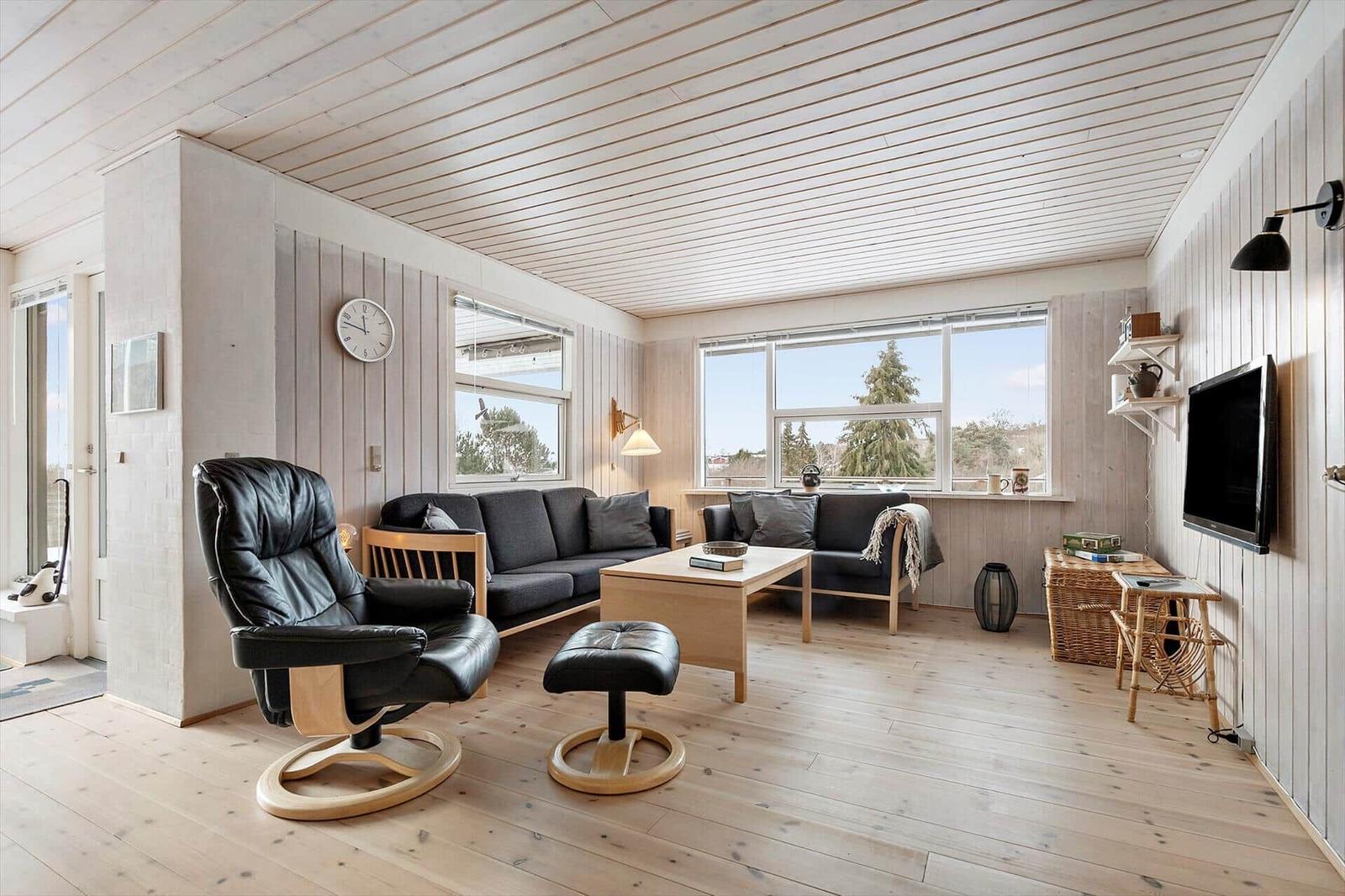 Living room with sofa, armchair, and TV mounted on the wall.