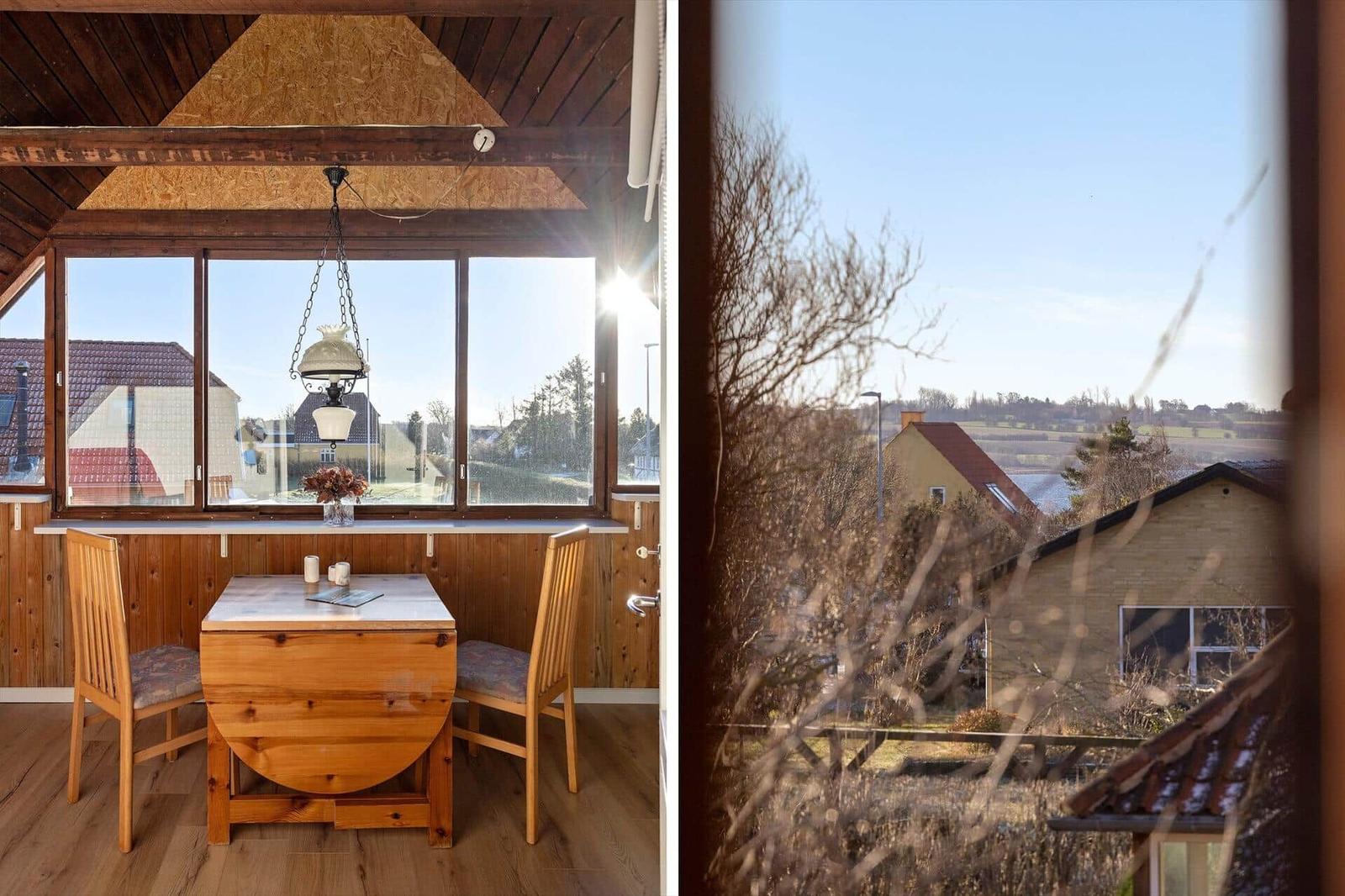 Dining area with wooden table and chairs. View of rural surroundings through windows.