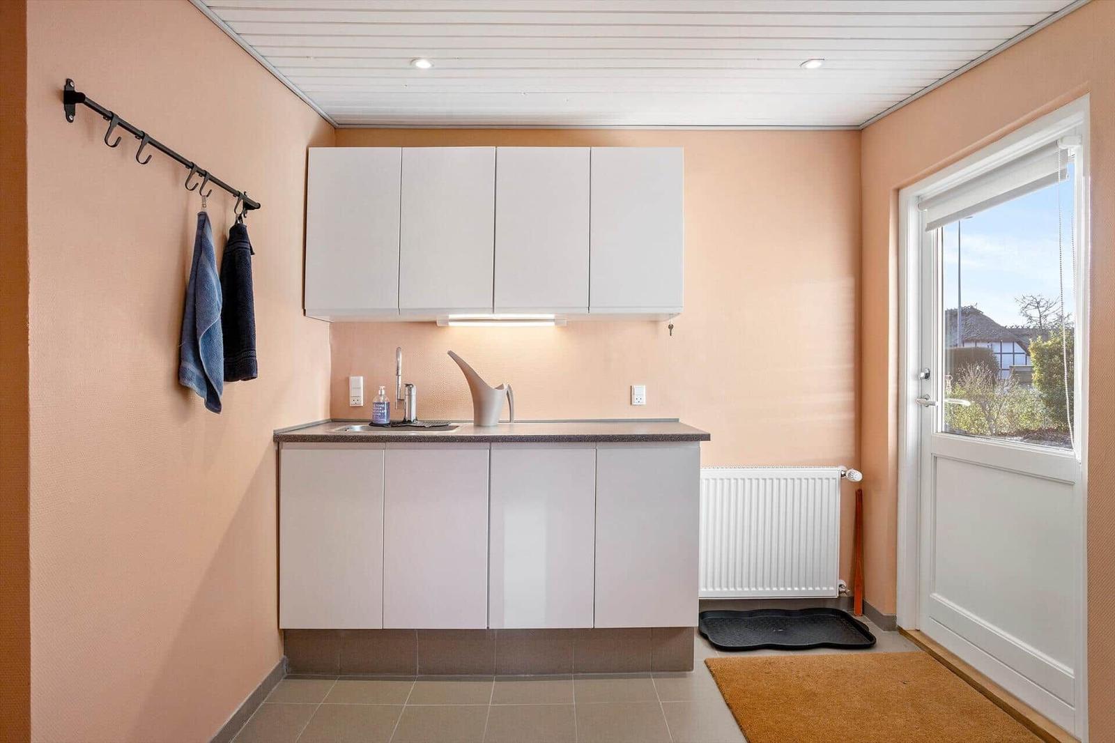 Kitchen area with white cabinets, sink, and window to the outside.