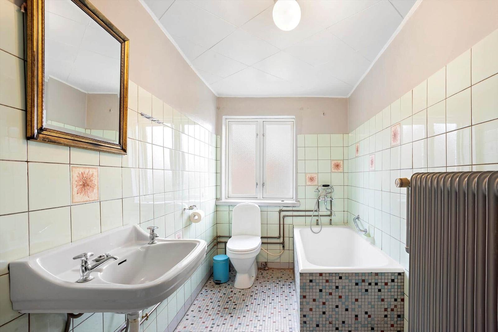 Bathroom with sink, toilet, bathtub, and mirror on the wall.