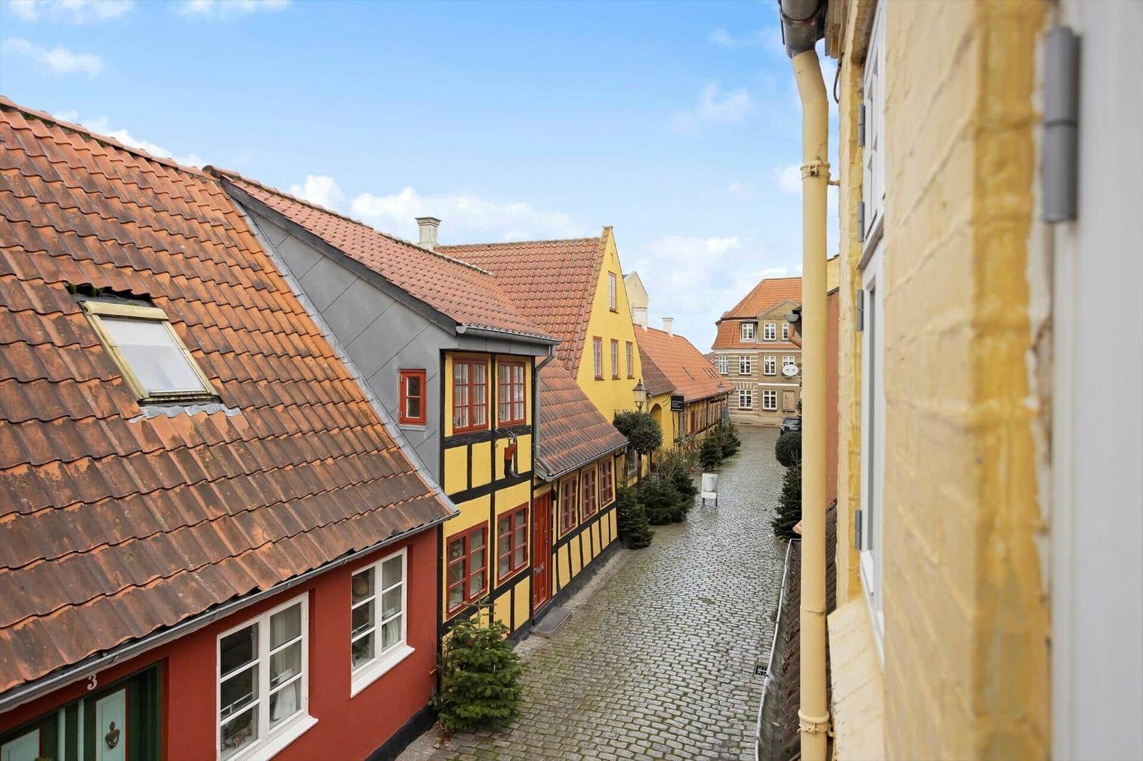 View of a cobblestone street with colorful houses and red tiled roofs.