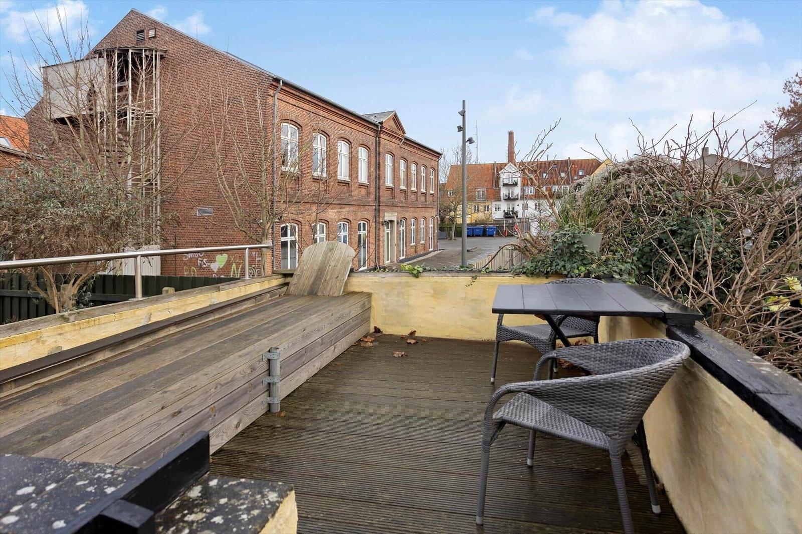 Terrace with table and chairs, view of brick building and street.
