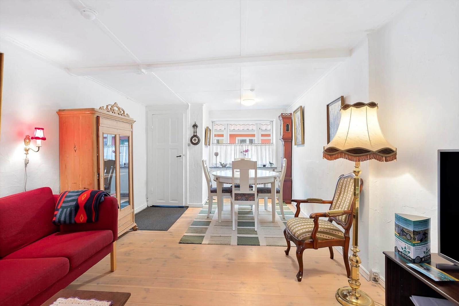 Living and dining area with red sofa, dining table, and floor lamp.
