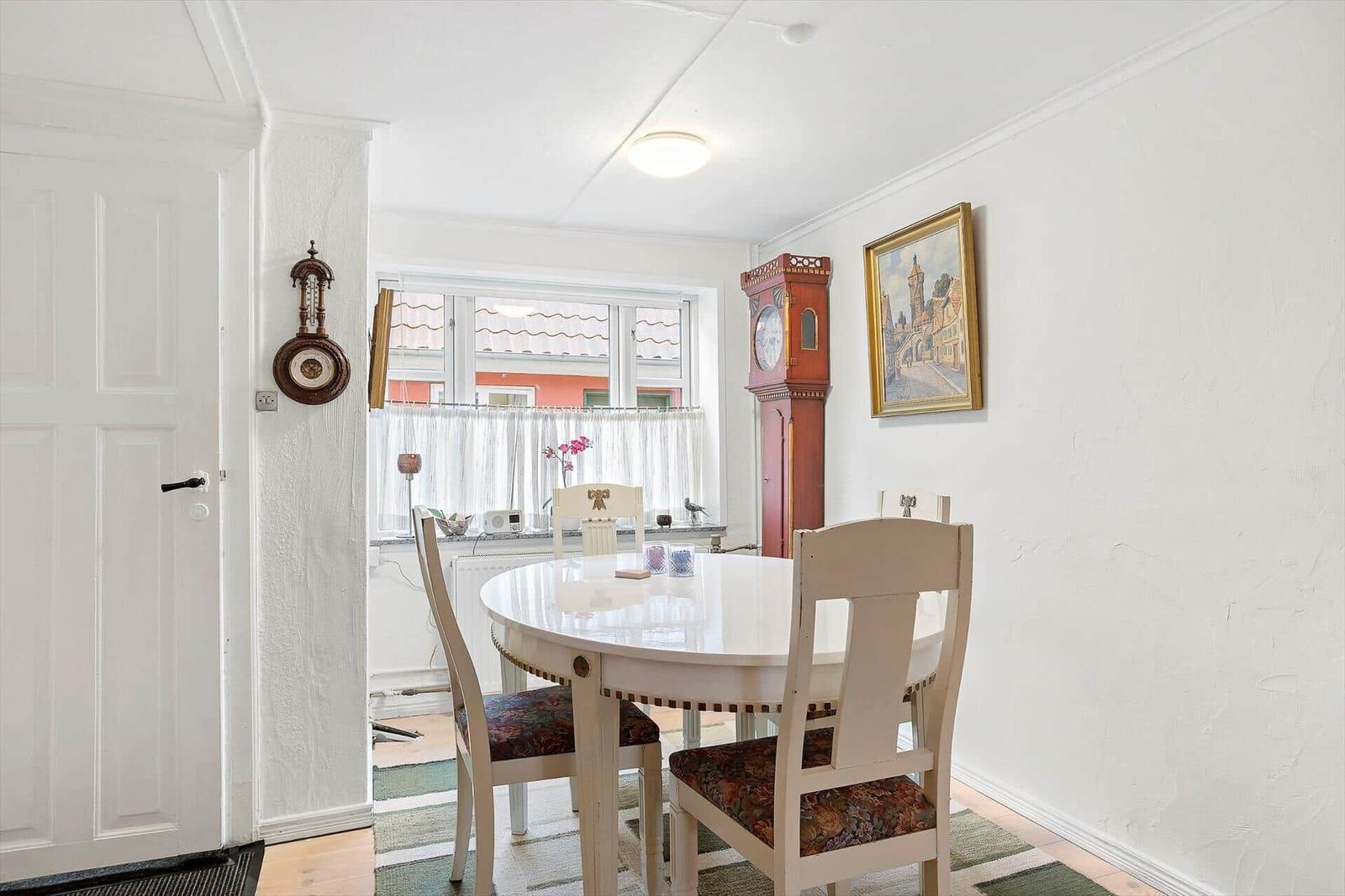 Dining room with round table, chairs, and tall wall clock