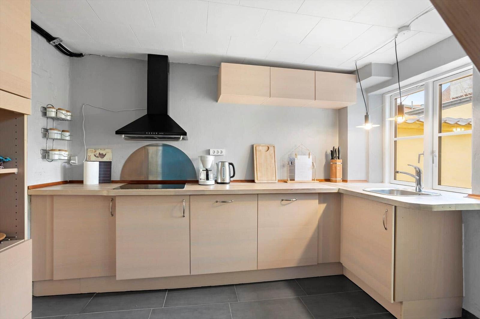 Kitchen with wooden cabinets, range hood, and window to outside.
