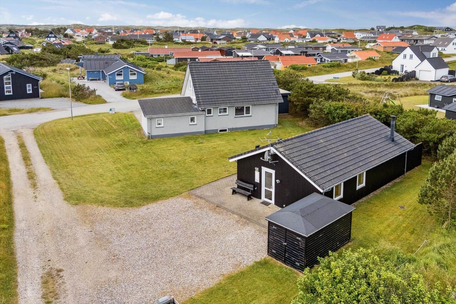 Schwarzes Ferienhaus mit Garten und Garage in einer ruhigen Wohngegend.