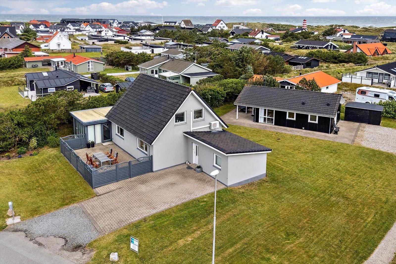 Modernes Ferienhaus mit Terrasse und Garten. Blick auf Strand und Küstenlandschaft.
