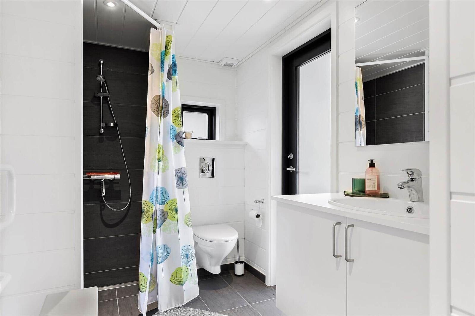 Bathroom with shower, toilet, and sink. Shower curtain with pattern.