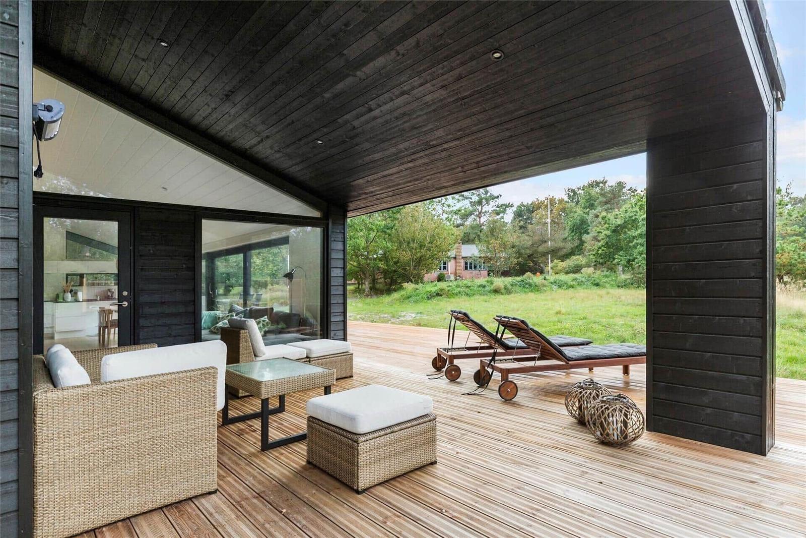 Deck with seating, lounge chairs, and view of green field.