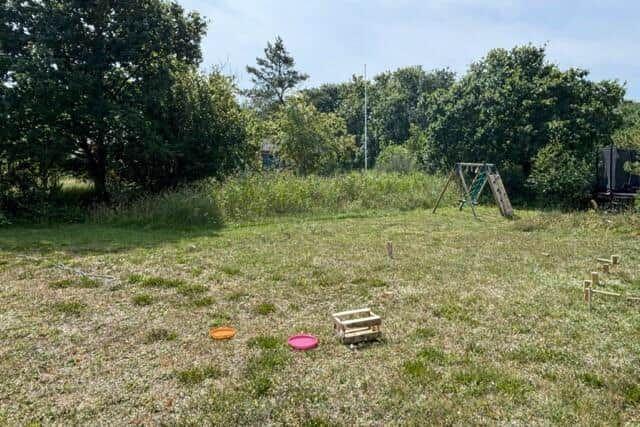 Green yard with playground and colorful frisbees.