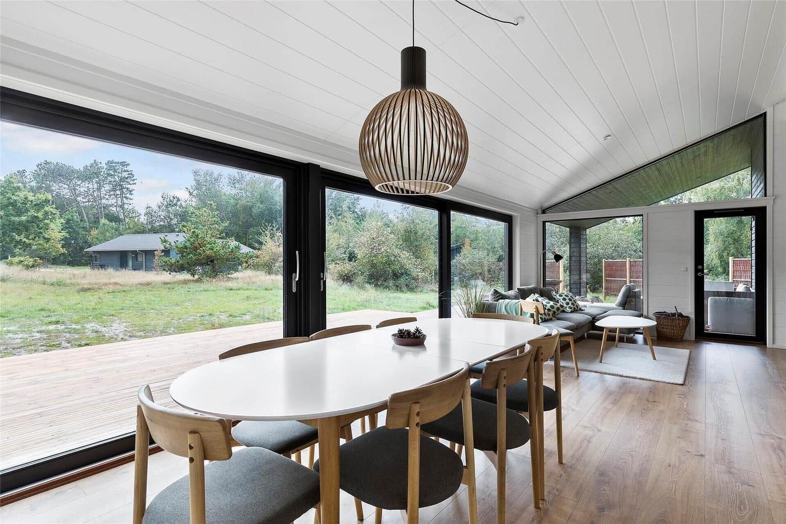 Dining area with table and chairs, large windows, and living area with sofa.
