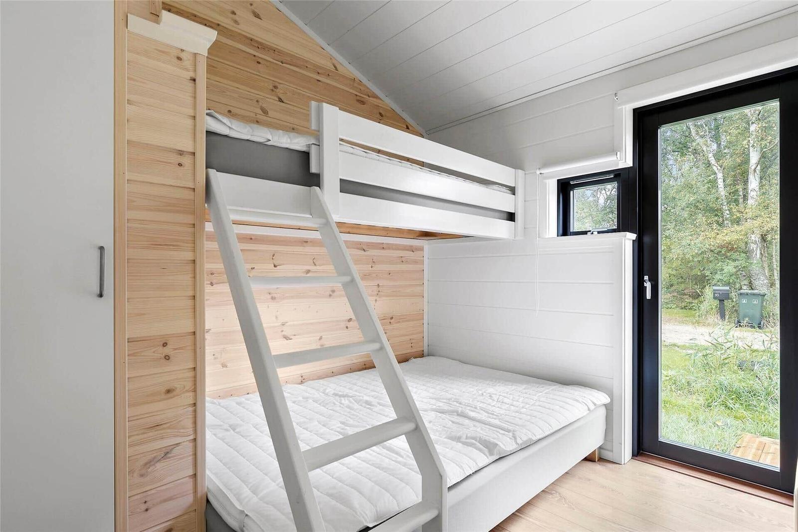 Room with bunk bed, wooden wall, and window to outdoor terrace.