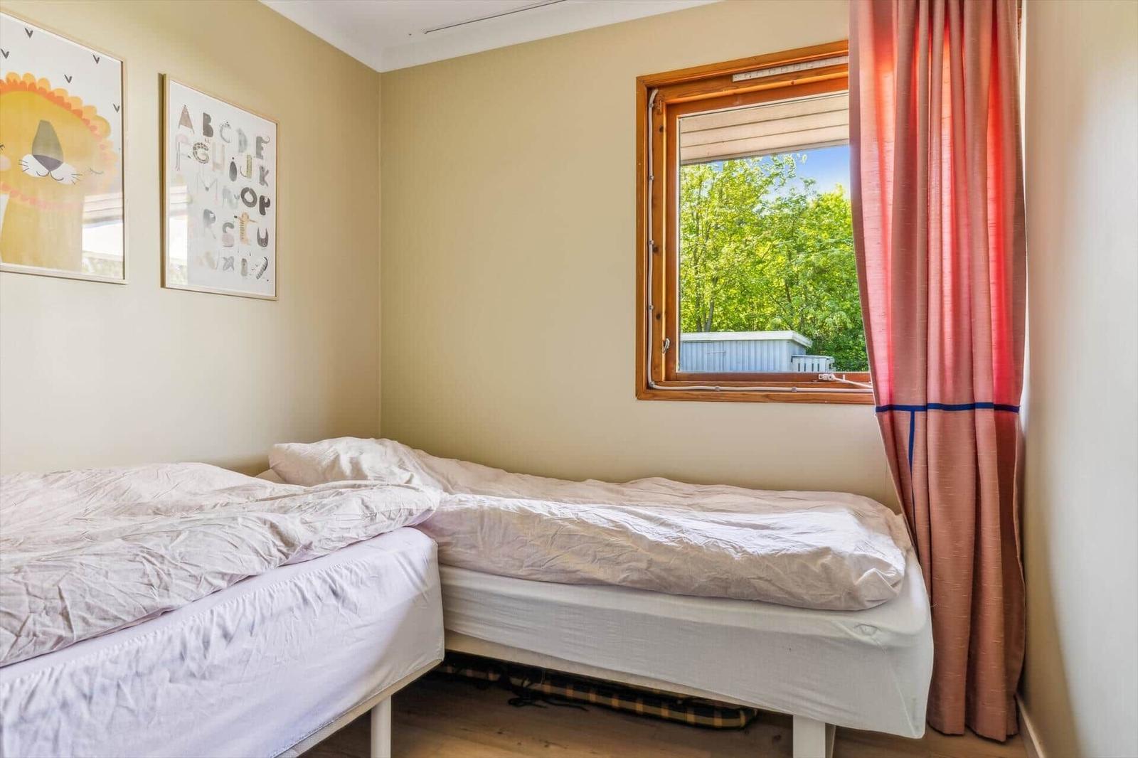 Two single beds with white bedding. Window with curtains and wall art.